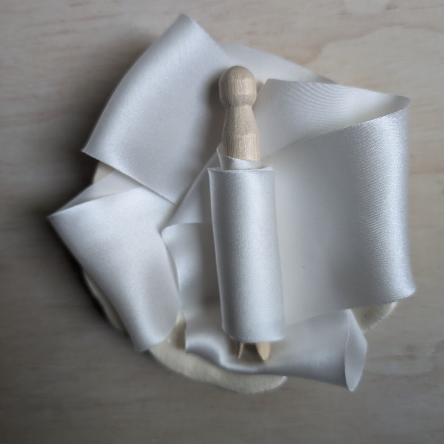 White silk charmeuse ribbon hand-cut on the bias, elegantly draped to highlight its sheen and fluidity.