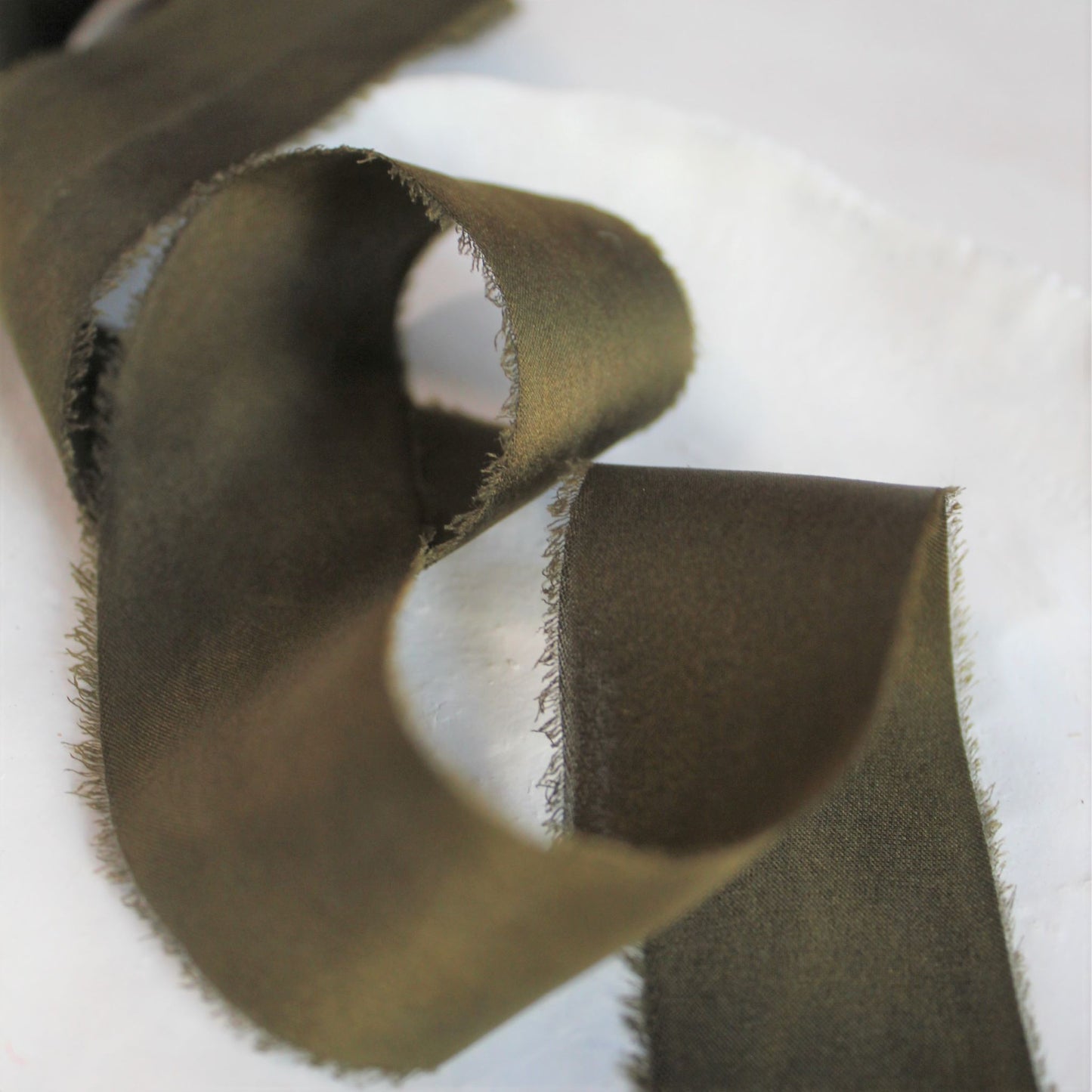 Close-up of hand-torn dark moss silk charmeuse ribbon