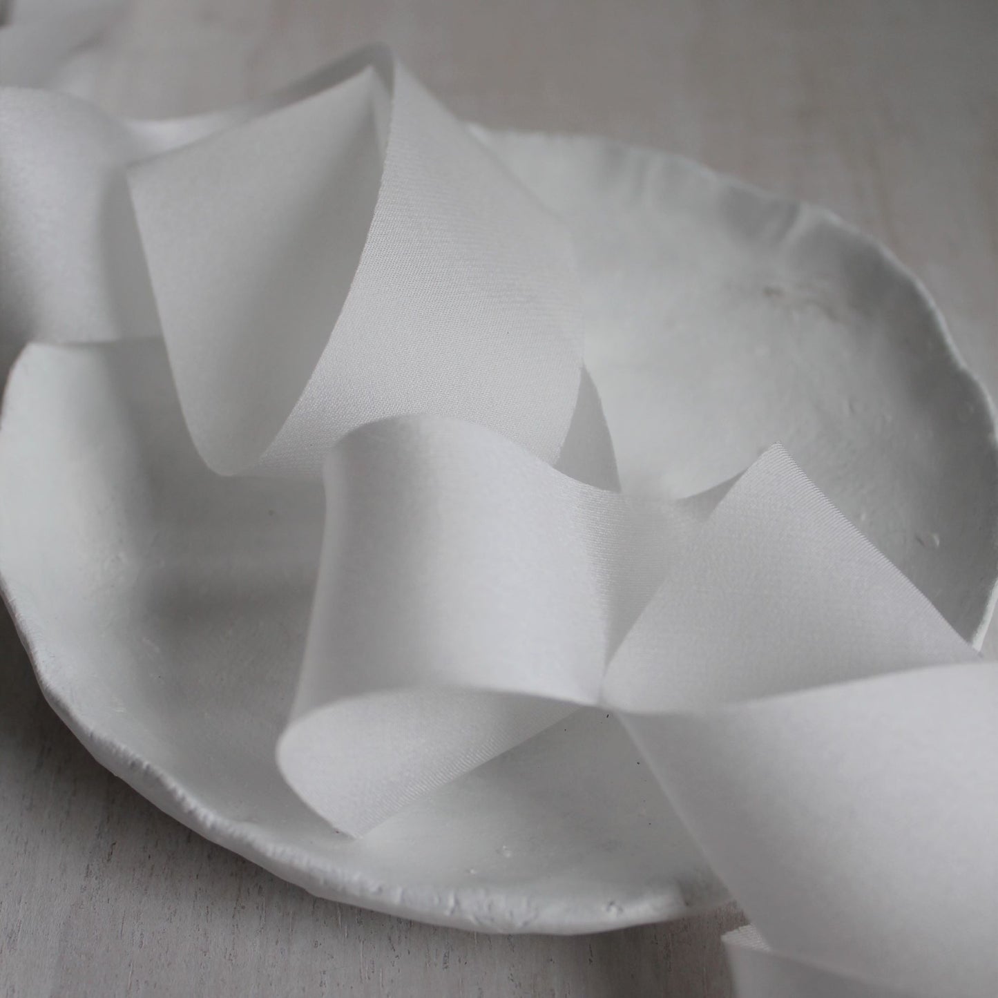 Glossy white ribbon with soft drape and matte reverse