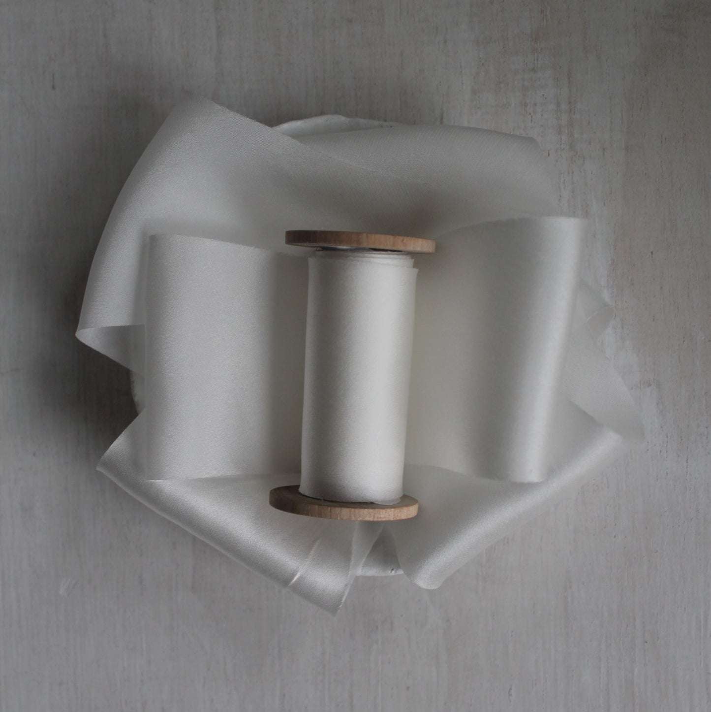 White bias cut silk charmeuse ribbon on wood spool