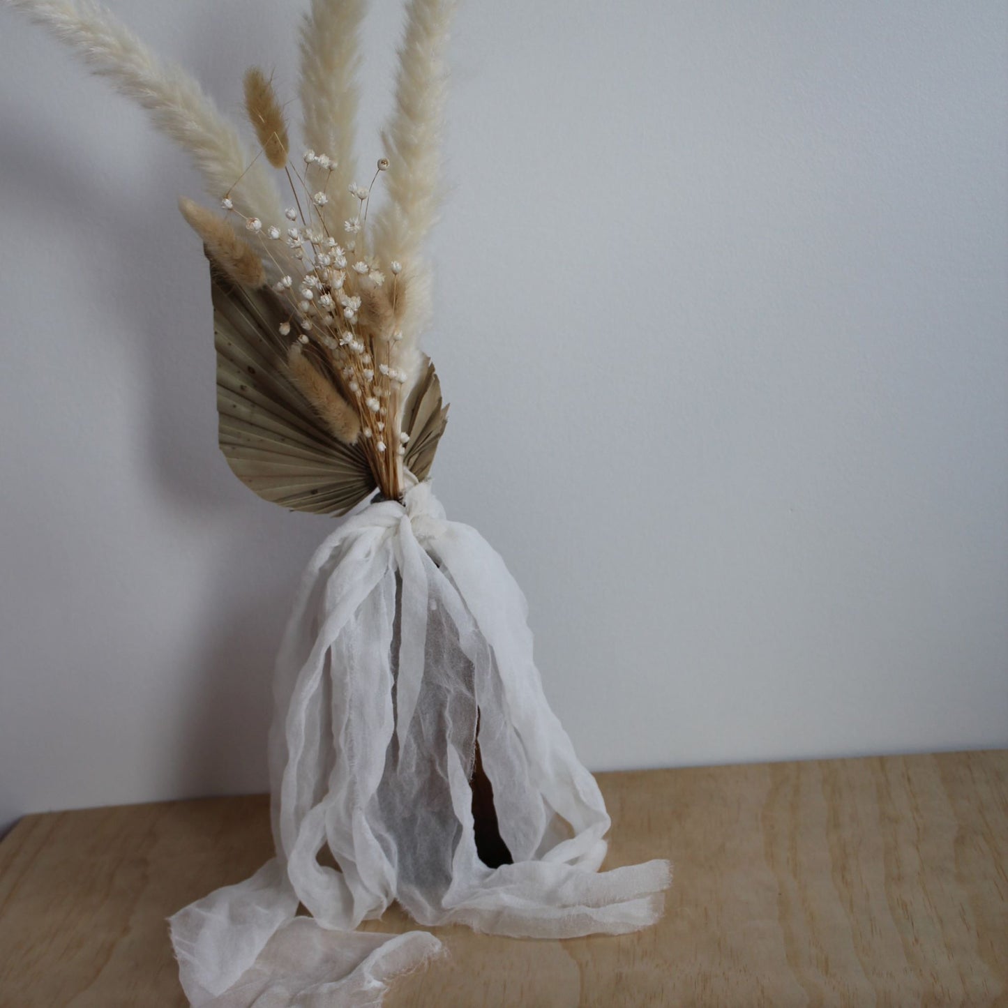 white chiffon ribbon tied around a bottle with dried floral in it