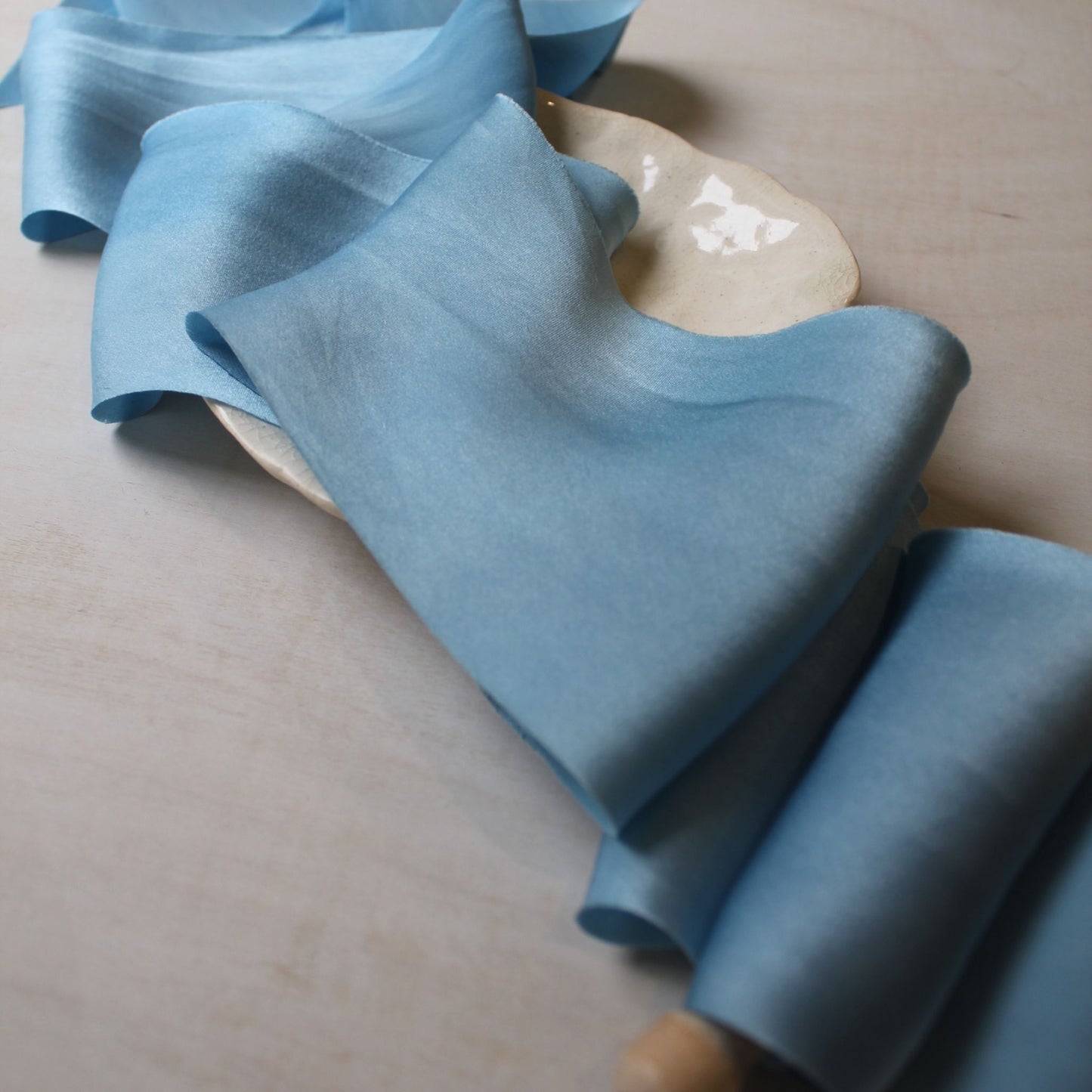 "Bias-cut pale blue charmeuse ribbon with natural indigo tones, ideal for wedding invitations and bouquet wrapping