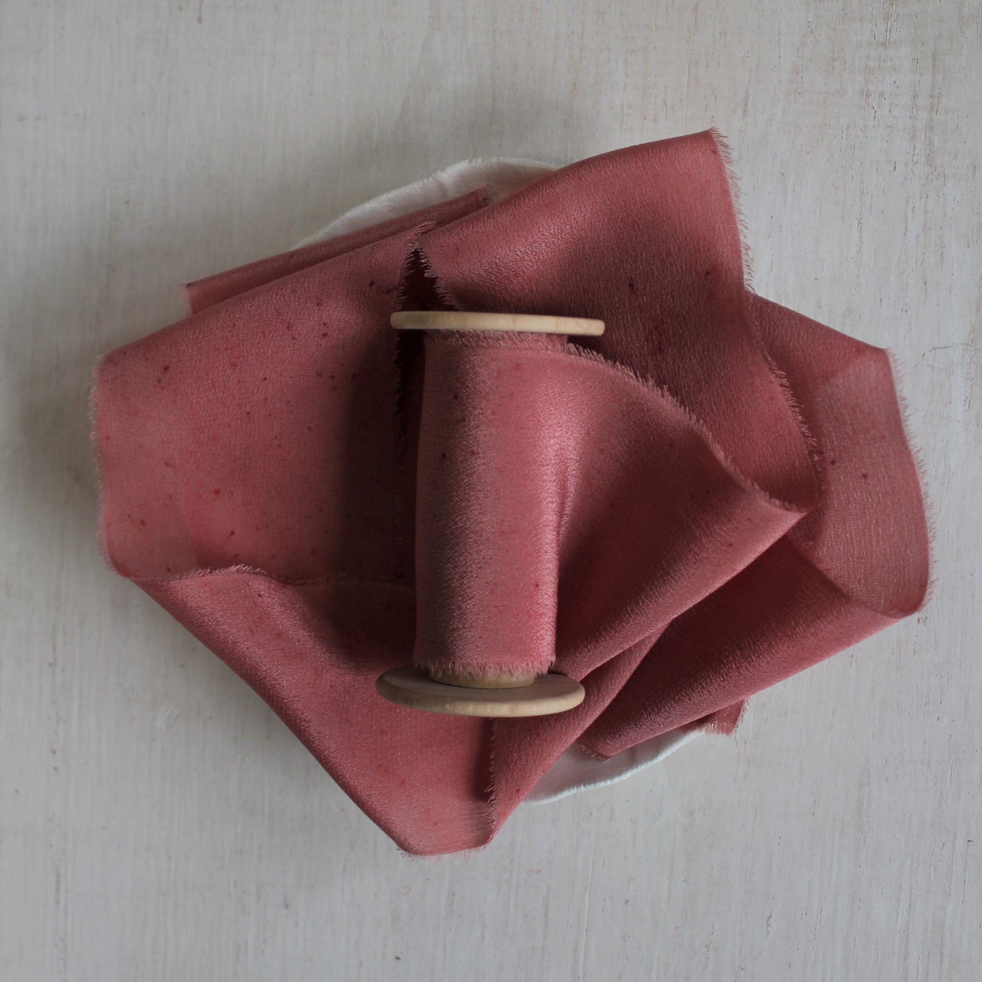 Berry silk crepe de chine hand-torn ribbon on wood spool.