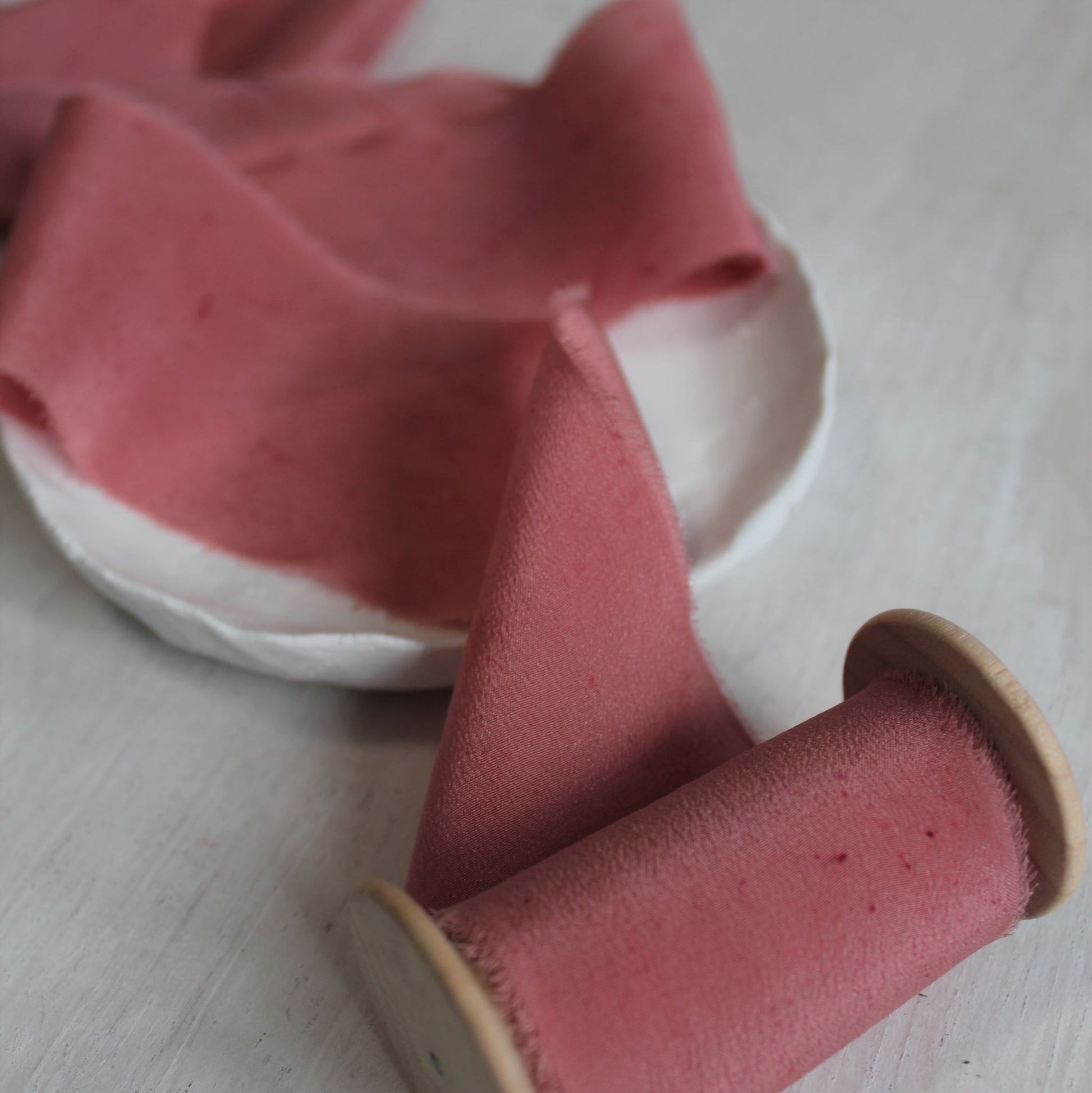 Close-up of hand-torn berry silk crepe de chine ribbon showcasing feathered edges.