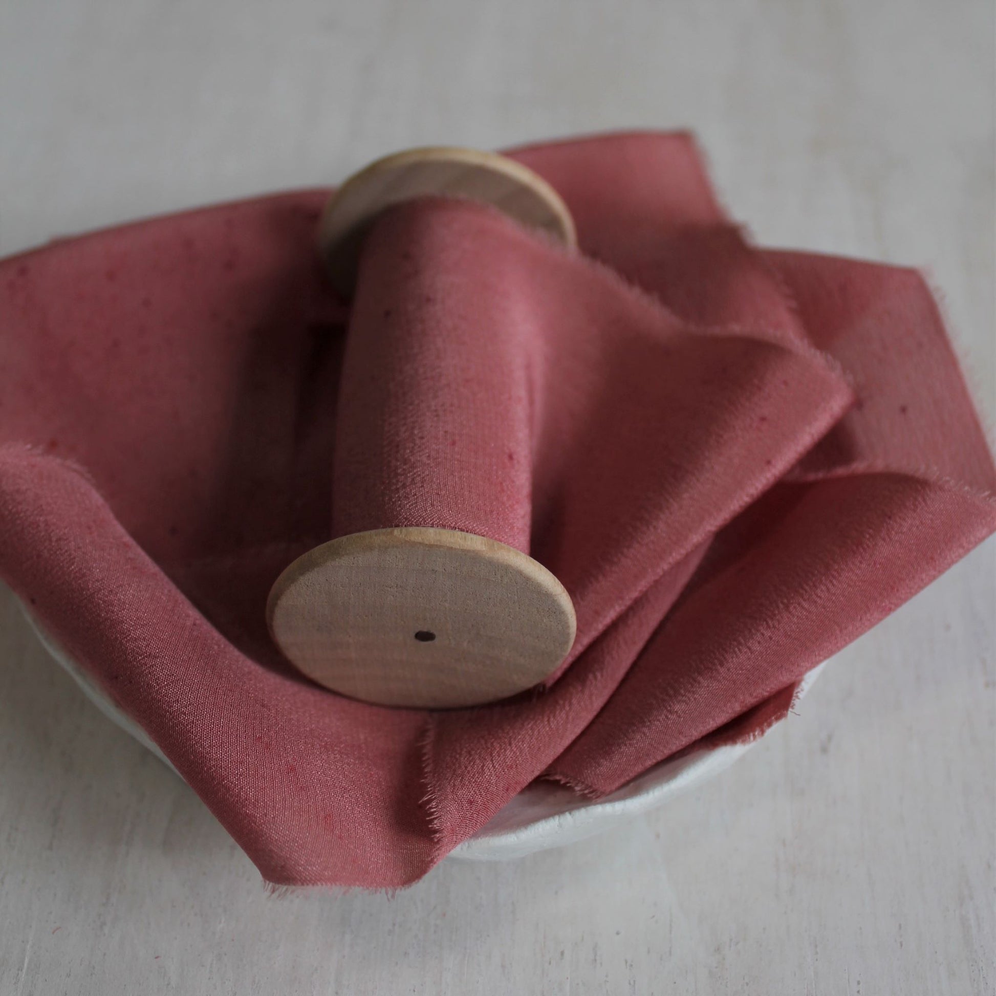 Texture detail of berry silk crepe de chine ribbon.