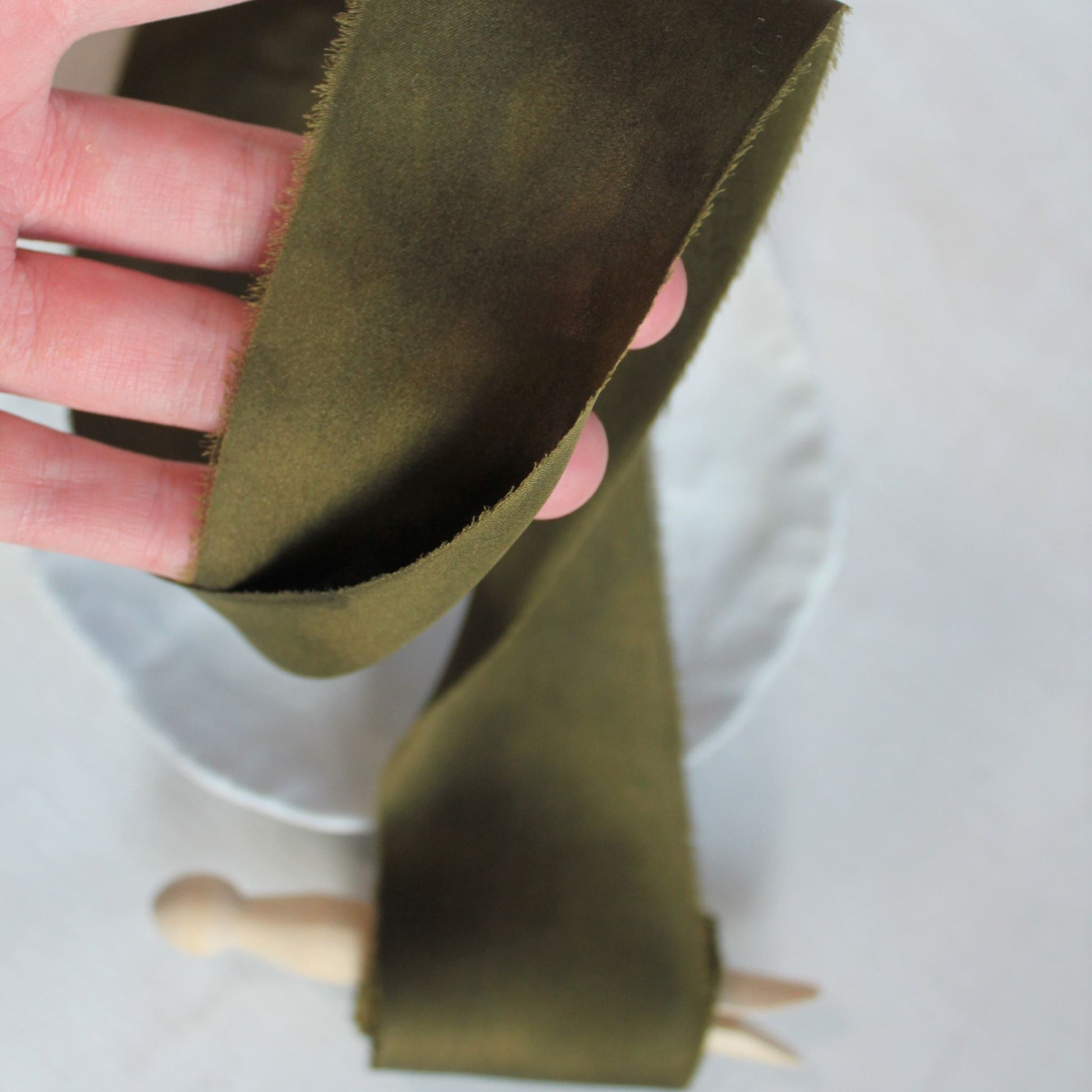 Close-up of hand-torn dark moss silk charmeuse ribbon 