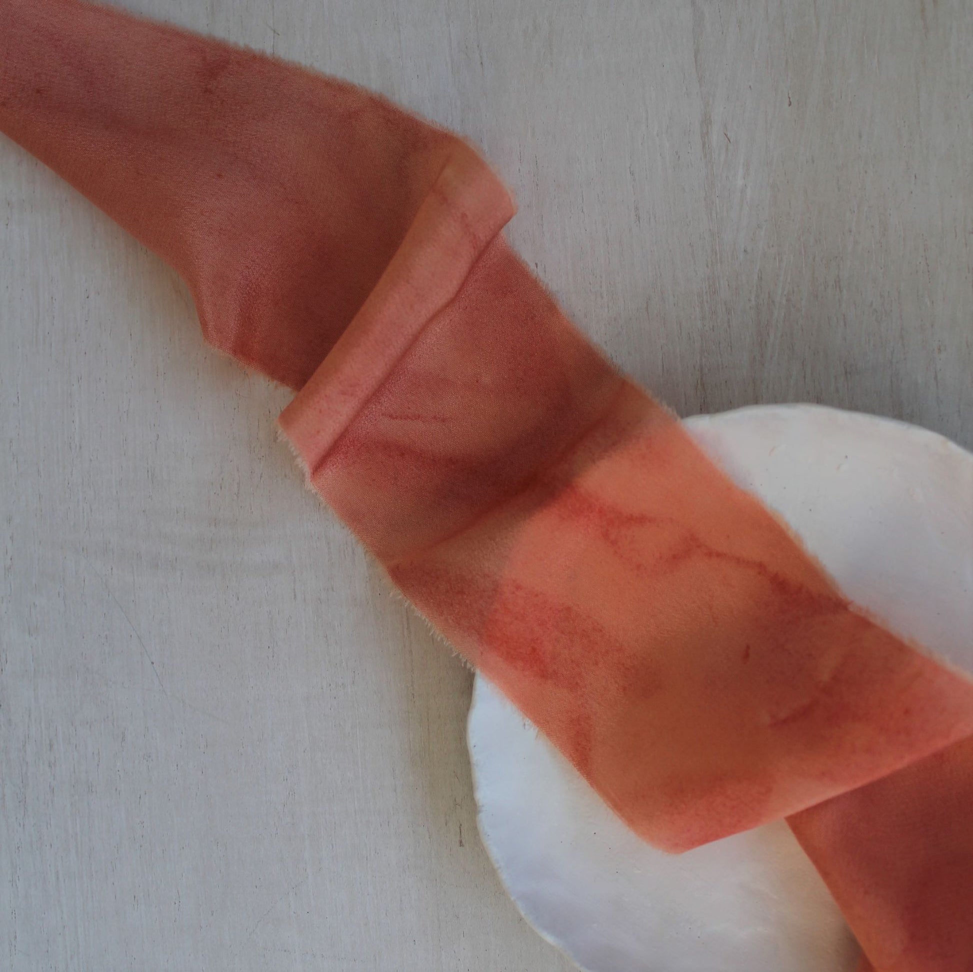 Naturally dyed silk ribbon in coral peach, hand-torn with a delicate texture for luxurious wedding stationery